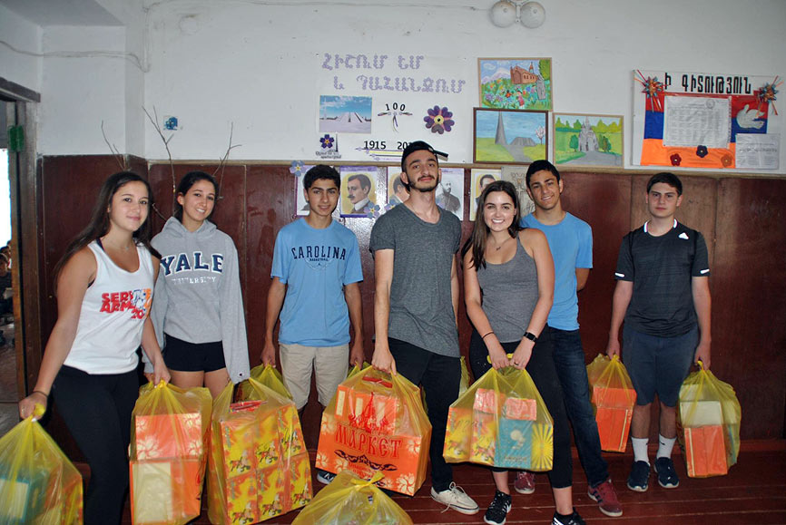 SERVICE Armenia 2016 participants assisting Catherine Conrow (2015 SERVICE Armenia participant and project sponsor) and her sister Lauren in the distribution of more than 200 pairs of new shoes to children at the Lchashen village school. Pictured left to right: Lauren Conrow, Catherine Conrow, David Barsamian, Levon Parseghov, Lily Woodall, Aram Parnigian and Aram Dadourian.